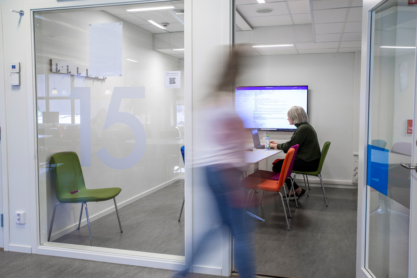 Bild på grupprum med personer som sitter och arbetar.